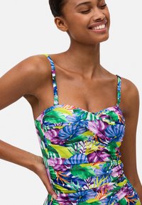 Bañador de estampado tropical multicolor con tirantes finos, detalles fruncidos y una forma ajustada. Fabricado en material ligero y suave.