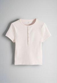 Top roz deschis cu mâneci scurte din tricot rib cu decolteu rotund și cu o pată frontală cu cinci nasturi.