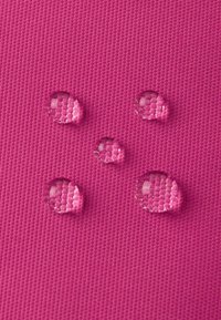 Leuchtend pinke strukturierte Oberfläche mit fünf klaren Wassertropfen, die ein gemustertes Gewebe unter den Tropfen zeigen.