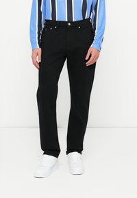 Mustadest denimist püksid klassikalise sirge lõikega, millel on metallnupp ja tõmblukk, küljetaskud ning puhas viimistlus.