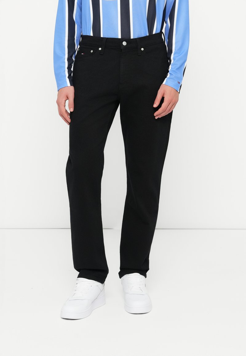 Mustadest denimist püksid klassikalise sirge lõikega, millel on metallnupp ja tõmblukk, küljetaskud ning puhas viimistlus.