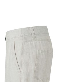 Primo piano di pantaloni di lino beige che mostrano la vita, l'asola per la cintura, la tasca laterale e la tasca posteriore con dettagli di cucitura visibili.