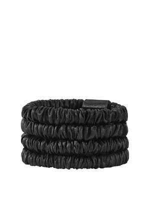 Set van vier zwarte satijnen scrunchies opgestapeld tegen een witte achtergrond.