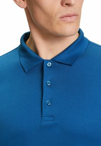 Blaues Poloshirt mit klassischem Kragen, einer Knopfleiste mit drei blauen Knöpfen und glattem Textilmaterial. Keine Muster oder Akzente.