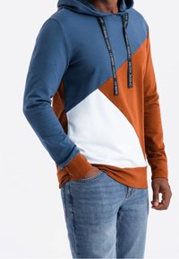 Sudadera con capucha que presenta un diseño de bloques de color geométrico en azul marino, naranja óxido y blanco. Fabricada con una suave mezcla de algodón.