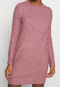 Abito in maglia in una leggera tonalità di rosso melangiato, con scollatura rotonda e maniche lunghe, dalla vestibilità leggermente rilassata e lunghezza sopra il ginocchio.