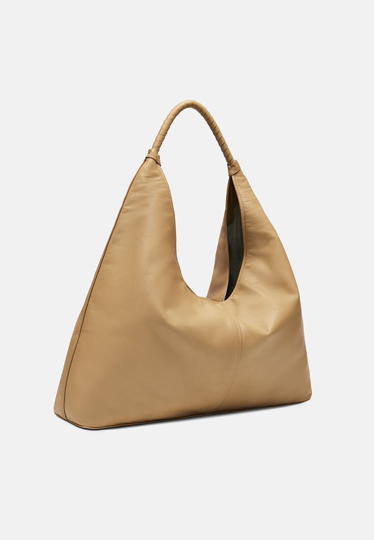 Beige leren hobo tas met een slungelige vorm en een enkele gevlochten handgreep. Heeft een ruime binnenkant en een gladde textuur.
