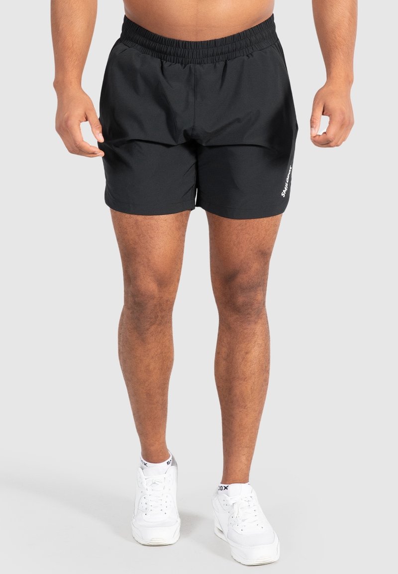 Bañador negro con cintura elástica, bolsillos laterales y un detalle del logo blanco en el lado izquierdo. Fabricado con tejido ligero.