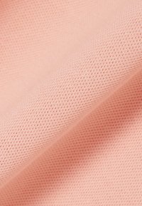 Primer plano de tela de punto suave de color rosa claro que muestra una textura fina y uniforme con pequeños lazos uniformes en el tejido.