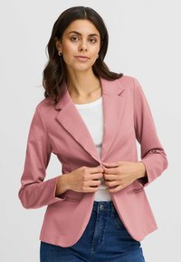 Lichtroze blazer met een geknipt kraag, knoopsluiting en twee frontzakken. Gladde textuur, lange mouwen, gecombineerd met een witte top.
