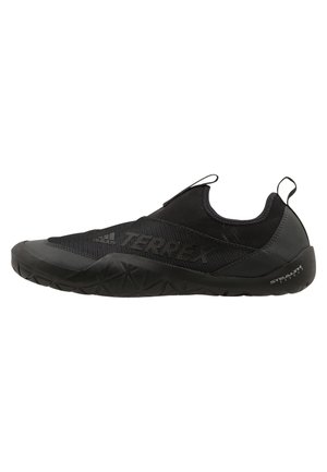 Chaussure de sport noire avec un upper en mesh et une semelle en caoutchouc, dotée d'un design slip-on et d'accents texturés sur la semelle pour une meilleure adhérence.