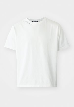 Biała bawełniana koszulka z okrągłym dekoltem. Posiada krótkie rękawy i subtelny tekst przy kołnierzu. Gładka faktura, luźny krój.