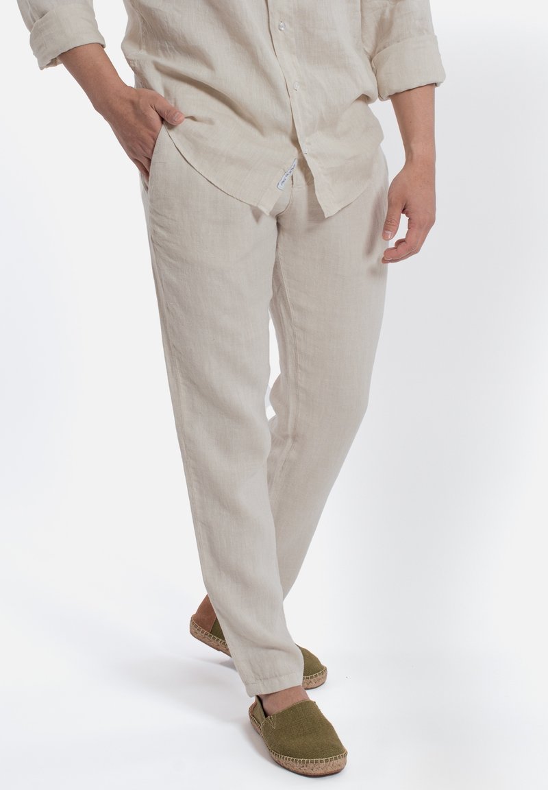 Linnen, beige broeken met een ontspannen pasvorm, zijzakken en een elastische tailleband, gecombineerd met groene espadrilles.