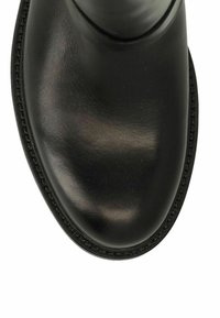 Scarpa in pelle nera lucida con punta arrotondata e cuciture visibili lungo il bordo della suola su sfondo bianco.