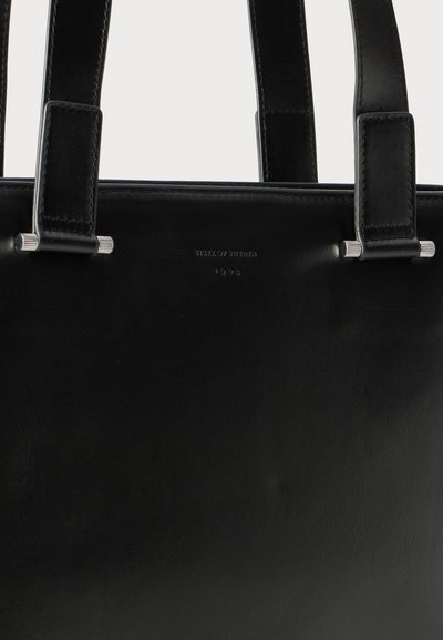 Schwarze Leder-Tote mit glatter Textur, zwei stabilen Griffen und silbernen Hardware-Akzenten. Verfügt über ein geprägtes Branding auf der Vorderseite.