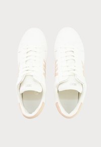 Fehér sneakers rózsaszín díszítéssel, sima bőr felsőrésszel, lapos fűzőkkel, perforált nyelvvel és három csíkkal az oldalán.