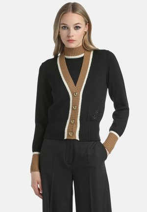 Črn cardigan z rjavimi in kremnimi črtami. Ima V-izrez, gumbnico in dekorativno žep. Z ribasto teksturo.