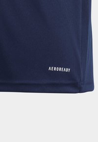 Camisa AEROREADY azul marino con una tela texturizada, que presenta un logo blanco en la parte inferior izquierda. El dobladillo está cosido cuidadosamente para mayor durabilidad.