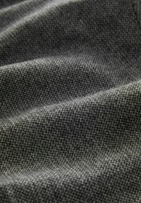 Texturiertem Stoff in Dunkelgrau mit einem kleinen geometrischen Muster, das ein weiches, gewebtes Aussehen mit sanften Falten zeigt.