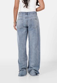 Jeans de mezclilla azul de tiro alto y pierna ancha con un acabado desvaído, que cuentan con bolsillos traseros y un diseño clásico de cinco bolsillos.