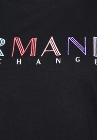 Černé tričko s vícero barvami vyšitým textem. Písmena jsou tučná s různými styly: "R", "MAN" v červené barvě a "CHANGE" v modré a fialové.