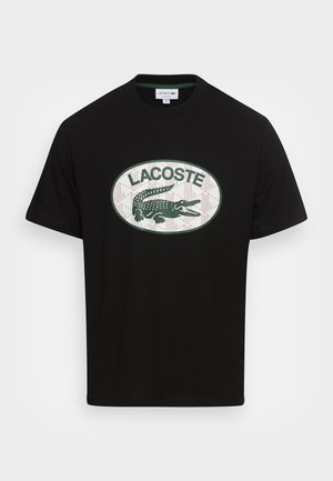Zwart T-shirt met korte mouwen en een ronde hals, met een groen-witte ovale logo met een krokodil en de tekst "LACOSTE" op de borst.