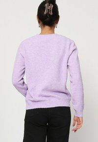 Pull en tricot lilas avec un col rond et des manches longues. Doté de poignets et d'un ourlet côtelés, d'une texture douce et d'un design uni.
