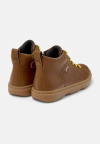 Botas de cuero marrón hasta el tobillo con cordones amarillos, cuello acolchado y superficie texturizada. Suela de goma marrón clara con detalles de costura.