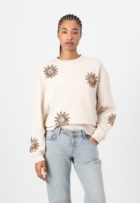 Beige sweatshirt with embroidered sun motifs in bronze on the front and sleeves. Features a round neckline and relaxed fit with ribbed cuffs.