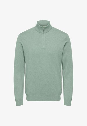 Helesinine rohelise tooniga kampsun kõrge kraega, poollukuga, soonikkoes allääre ja varrukatega. Pehme tekstuur, pikad varrukad, minimalistlik disain.