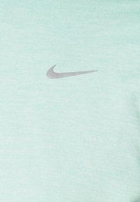 Jasnoniebieska tkanina z małym szarym logo Nike w kształcie znaku Swoosh umieszczonym na środku powierzchni.