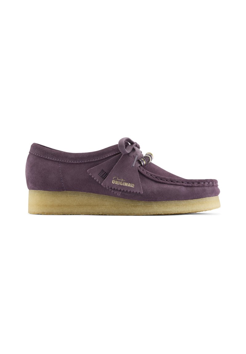 Purple suede moccasin-style shoe with beige crepe sole, tassels, and "Clarks ORIGINALS" branding on side.