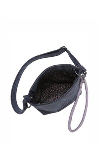 Borsa a tracolla blu navy con una texture morbida, una tracolla ampia e un manico intrecciato viola. L'interno presenta un motivo a pois nei toni del rosa.