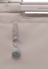 Lysebeige tote-taske med stofhåndtag og påsat sølvmetal nøglering med indgraveret "KAPTEN & SON" logo.