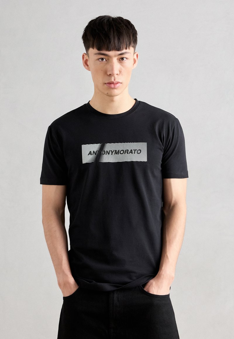 Black cotton t-shirt featuring a grey striped rectangular graphic with the text "ANONYMOUS" in bold letters across the front.