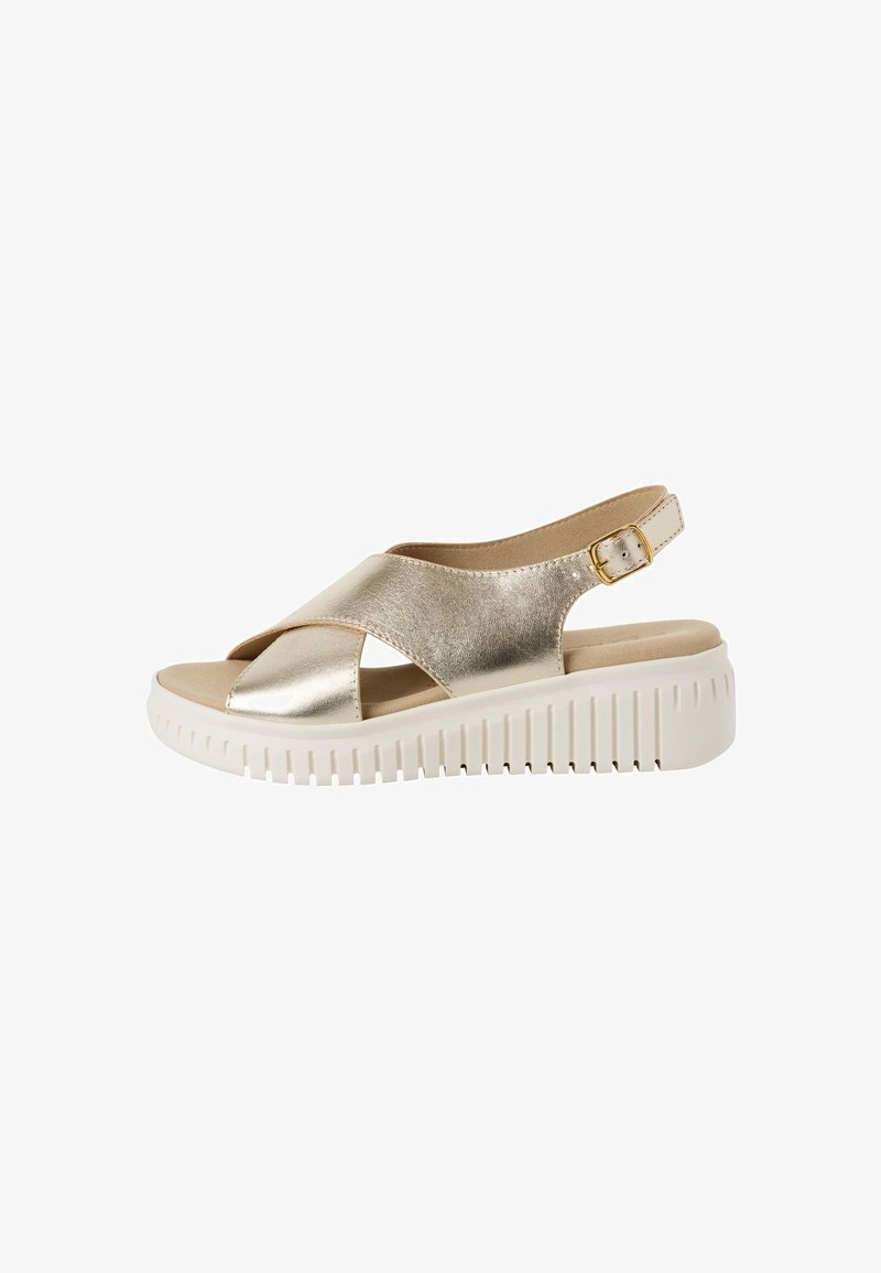 Sandale métallique dorée avec des brides croisées, design à talon ouvert, et une semelle blanche à plate-forme avec une texture striée.