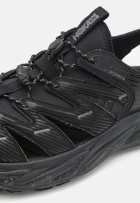 Czarne buty sportowe z textured upper, charakteryzujące się smukłym designem, trwałym materiałem, odblaskowymi akcentami oraz amortyzowaną podeszwą z nakrapianym detalem.
