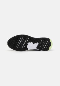 Semelle de chaussure de sport en noir et blanc avec un motif texturé, dotée d'une accentuation distincte jaune-vert au niveau du talon et d'une zone centrale lisse.