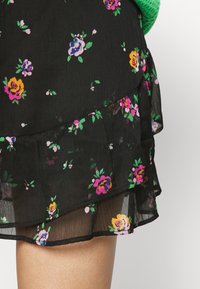 Svart blommig kjol med lager på lager och volangnedre del. En fin och lätt stoff med livliga lila, gula och gröna blommönster genom hela.