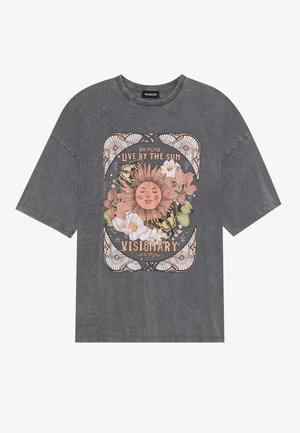 T-shirt ample gris en coton avec un design graphique coloré représentant un soleil, des fleurs et des papillons, encadré de motifs délicats.