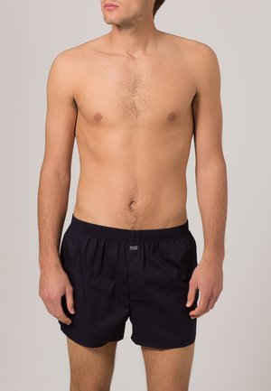 Navyblaue Baumwollboxershorts mit elastischem Bund, ausgestattet mit einem kleinen Logo an der Vorderseite und einem lockeren Schnitt.