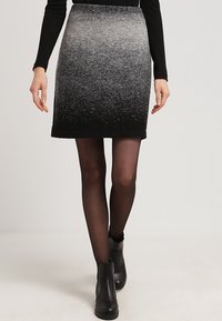 Grå ombrekjol med en strukturerad finish som övergår från ljusgrå till svart. Matchad med svarta strumpbyxor och ankelskor.