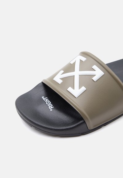 Σανδάλι slide με μαύρη εσωτερική σόλα που φέρει την ετικέτα «ΔΕΞΙΑ» και ελιάς λουράκι με τέσσερα λευκά βέλη κατεύθυνσης που διασταυρώνονται στο κέντρο.