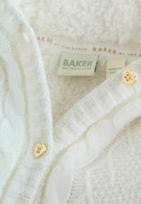 Weißer Strickcardigan mit Kabelmuster, goldenen, herzförmigen Knöpfen und weichem, strukturiertem Futter mit einem "BAKER"-Label.
