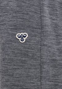 Grau strukturierten Stoff mit einem kleinen gestickten Bienenlogo in Marineblau und Weiß auf der linken Seite. Einfaches und minimalistisches Design.