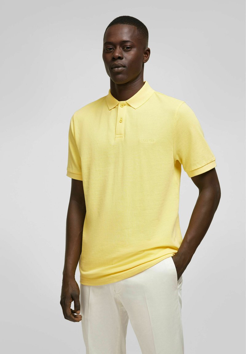 Geel polo shirt van gestructureerde stof met een kraag en drie knopen; heeft korte mouwen en subtiele geborduurde logo.