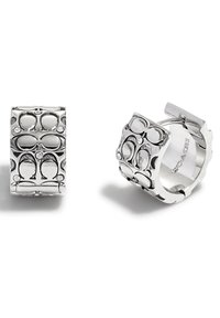 Boucles d'oreilles en argent en forme de cerceau avec un design en motif présentant des formes entrelacées et de petites accents transparents. Texture lisse avec une finition polie.