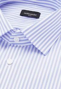 Chemise à rayures bleu clair et blanc avec col pointu et boutons blancs, avec une étiquette noire "seidensticker uno" à l'intérieur du col.