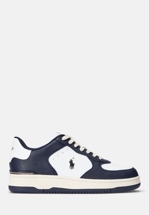 Baskets en cuir bleu marine et blanc avec surface texturée, lacets beige clair, perforations et petit logo noir sur le côté.