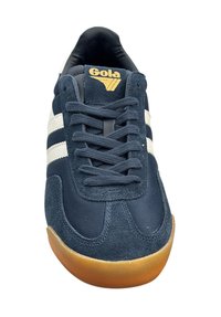 Sneaker blu navy con strisce bianche, materiali in suede e rete, suola in gomma e logo dorato sulla linguetta. Lacci piatti di colore grigio scuro.